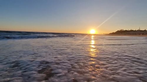 Golden Sunset on Beach Frothy Waves Roll on Sand of Beach Under Low Sunlight Slow Motion Photography