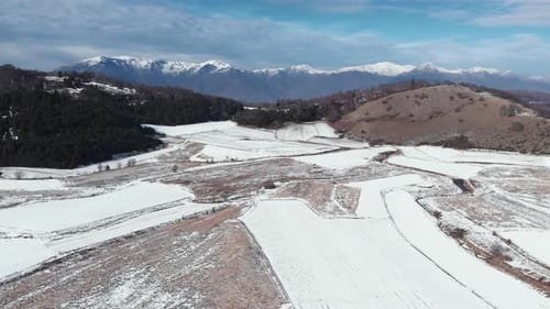 Schneebedeckte Bergfelder und Gipfel im Hintergrund einer Drohne an einem sonnigen Wintertag