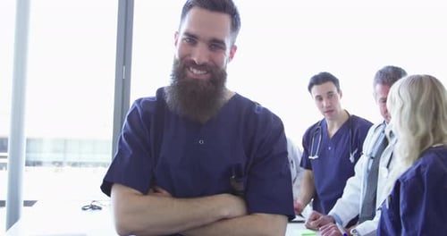 Confident Relaxed Surgeon Doctor At Hospital With Team Of Doctors In Background