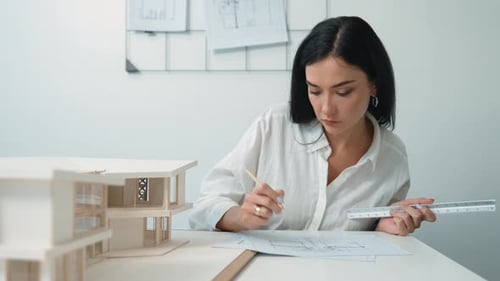Arquitecto que usa una regla para medir un modelo de casa en una oficina moderna. Inmaculado.