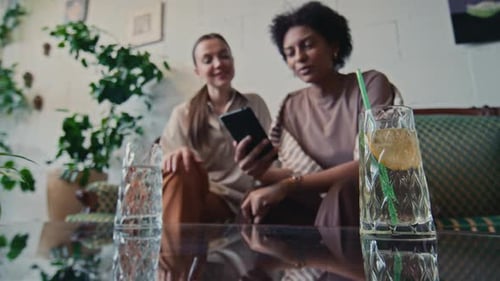 Two Women Looking at Phone Together Indoors