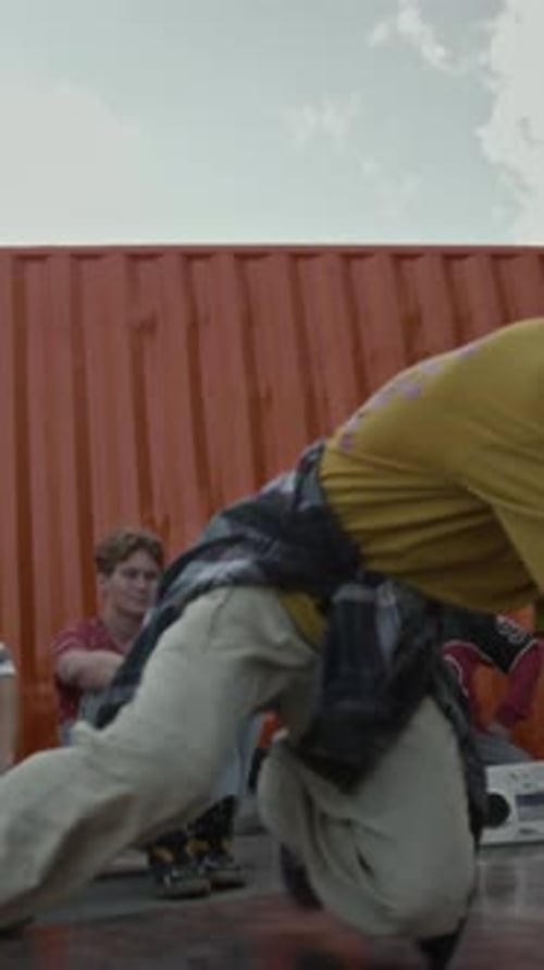 Vertical of Talented Teenage B-Boy Breaking Outdoors in front of Friends