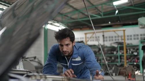 The mechanic is fixing a car at a car repair shop.