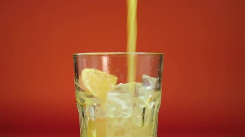 Pouring Orange Juice into Glass with Ice