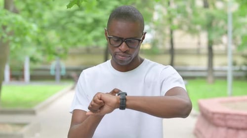 Young African Man Using Smart watch in a Park