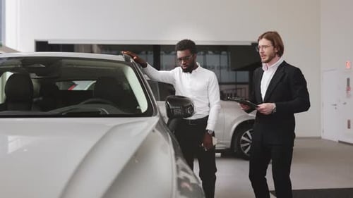 Man Inspecting Car with Salesman at Dealership