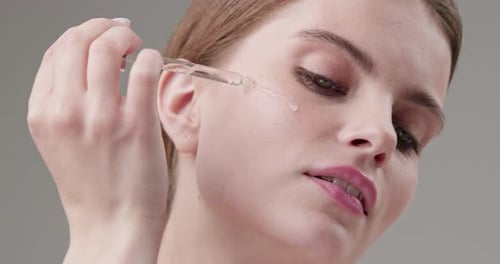 Woman Applying Skincare Serum with Dropper Close Up