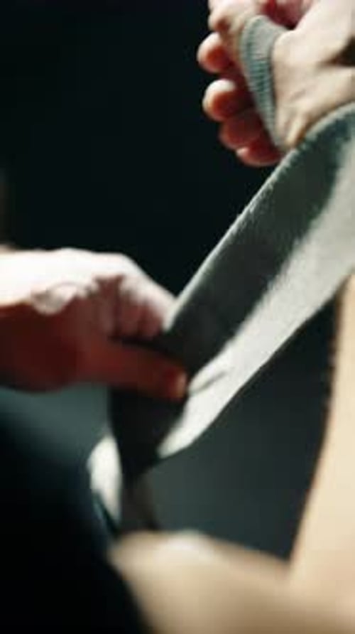 Athlete Wraps Hand with Bandage in Dark Gym