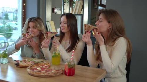 Fröhliche Freundinnen essen Pizza im Restaurant