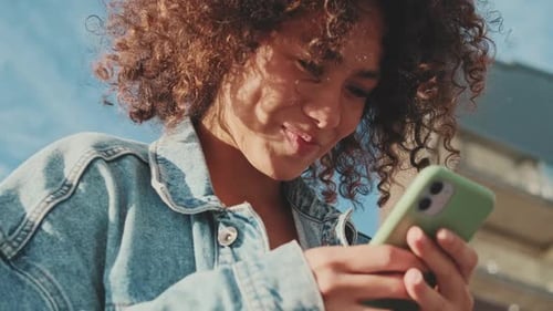 Smiling Woman Uses Smartphone Device Outdoors
