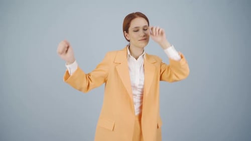 Stylish Woman Dancing with Energy in Orange Suit
