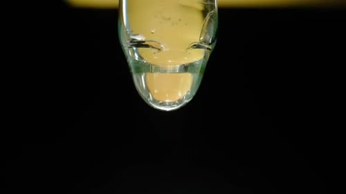 Drop of Transparent Liquid Oil Serum or Tincture Dripping From Glass Pipette on Black Background