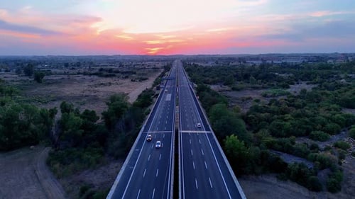 Mehrere Autos fahren während eines farbenfrohen Sonnenuntergangs auf einer Autobahn