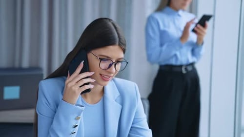 Business Woman Talking on Phone While Using Laptop