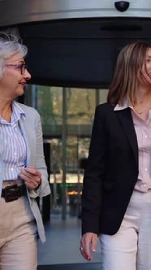 Mujeres empresarias conversando al salir de un edificio de oficinas moderno