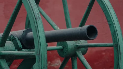 Ancient Green Cannon Against Red Wall A Glimpse Into History and Warfare