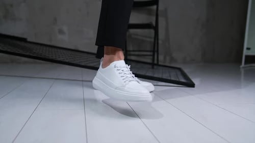 Male footwear demonstration in studio. Model wears white stylish comfortable shoes