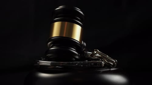 The judge's gavel and handcuffs rotate on a black background.