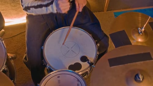 Unrecognizable Person Striking Snare Drum with Drumsticks in Dark Music Studio