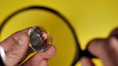 Examining Diamond Gemstone Under Magnifying Glass on Yellow