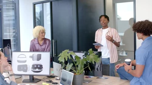 Équipe collaborant au bureau, discutant de la conception de casques VR sur des écrans d'ordinateur