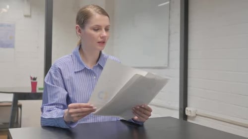 Young Woman Reading Business Documents in Office