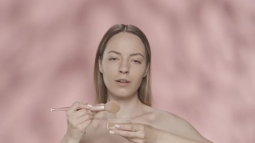 A Woman Dips a Makeup Brush Into a Jar of Powder Blush and Applies Cosmetics to Her Face Portrait of