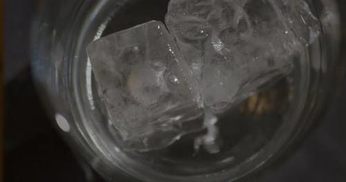 Barman putting Ice Cubes in a glass with Vodka - Top View