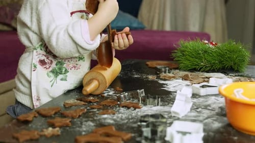 Child making christmas cookies using rolling pin and cookie cutters