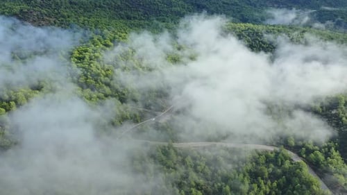 Vue aérienne de la route serpentine partiellement cachée parmi les nuages
