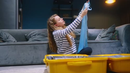 Young Woman Packing Suitcase for Travel at Home