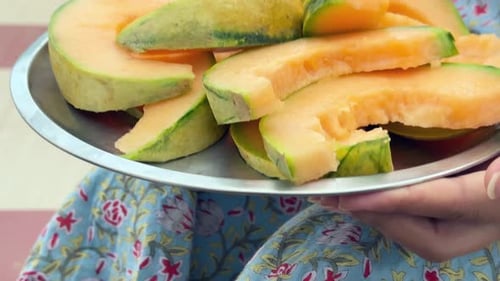 Hands Holding Tray of Sliced Cantaloupe Melon