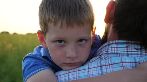 Boy Being Embraced by Father at Sunset