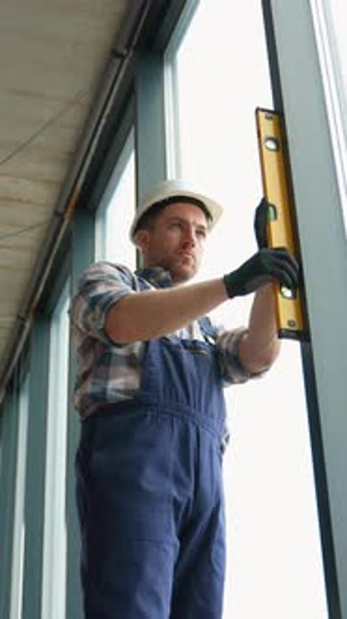 Construction Worker Checking Window Frame Verticality with Spirit Level