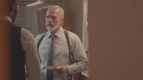 Mature Detective Speaking to Colleague in Office