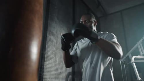 Boxer Training Hitting Punching Bag African American Sweated Sportsman Practicing Punches in Gym