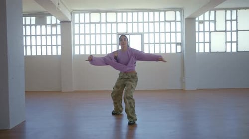 Young Woman Dancing Freely in Light Studio