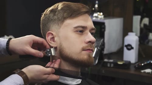 Young Handsome Man Enjoying a Professional Beard Trim at a Stylish Barbershop