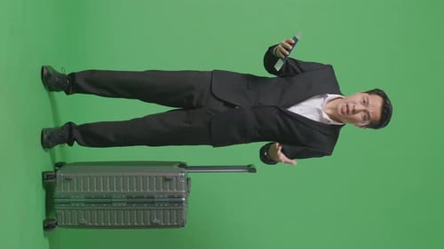 Wondering Asian Businessman Traveler With Luggage Standing Doubtfully In The Green Screen