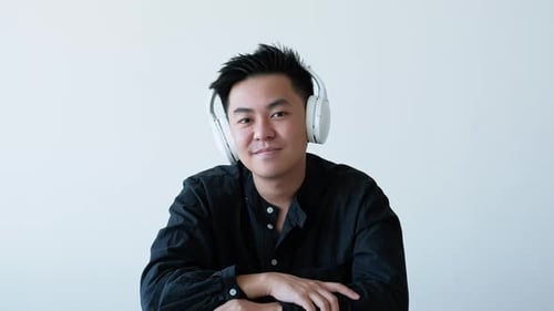 Man Wearing Headphones Speaking To Camera Indoors