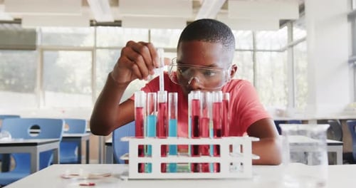 In school, boy conducting science experiment with test tubes in classroom laboratory