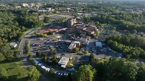 American hospital campus with buildings in brick design during sunset time. Parking area with cars