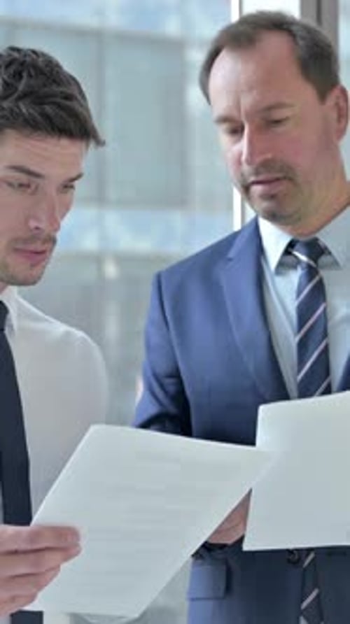Businessmen Discussing Paperwork in Modern Office