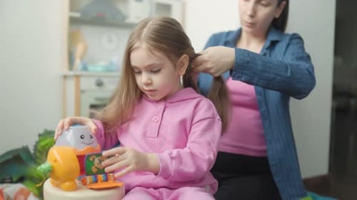 Mom Braids Daughter's Hair in Home Setting