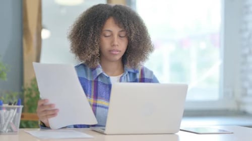 Woman Smiling While Working On Laptop And Reviewing Paperwork