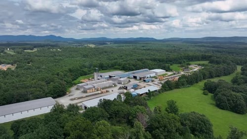 Industrial area, factory and warehouses surrounded by green forest trees in Virginia. Cloudy summer