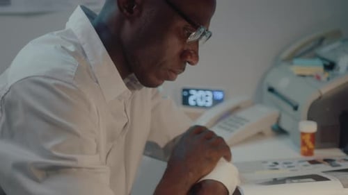 Man at Desk Working Late with Bandage