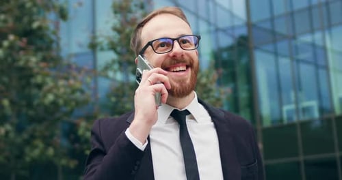 Portrait of man talking on mobile phone in city business district. Confident young businessman