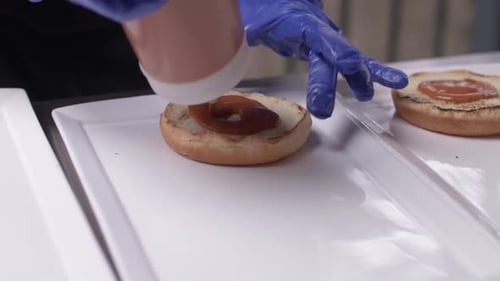 Cook Prepares Burger Buns with Creamy Orange Sauce