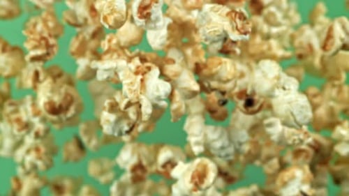 Delicious Popcorn Flying on Green Background in Slow Motion